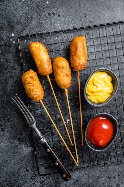 Cani di mais fritti con senape e ketchup Sfondo nero Vista dall'alto