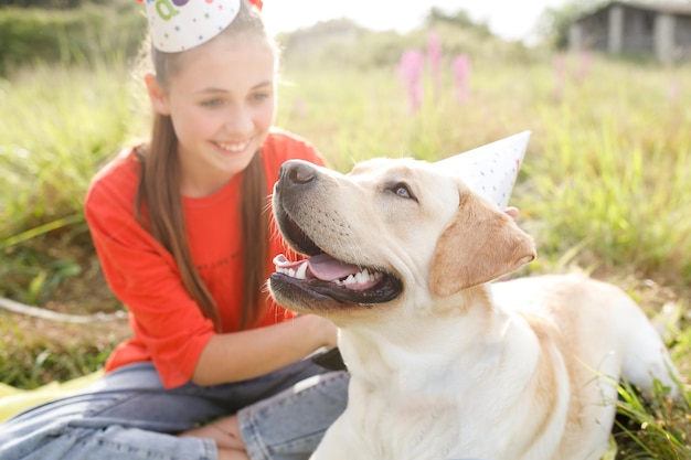 Cani Labrador un compleanno un ritratto di un cane con un cappello festivo primo piano in natura lo sfondo con la ragazza è sfocato
