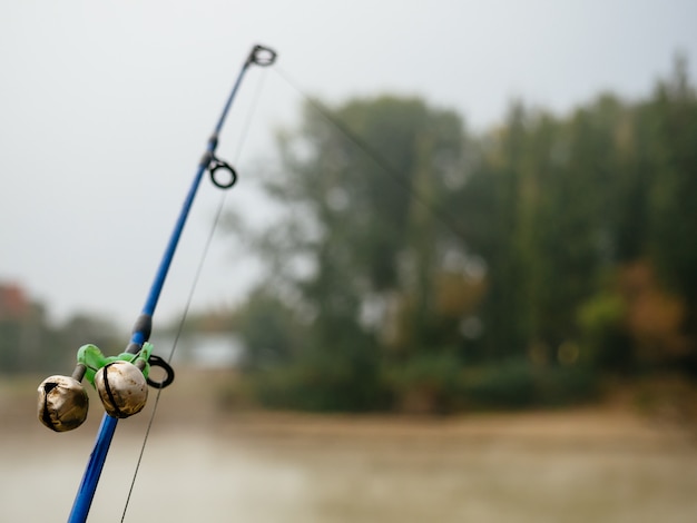 Canna da pesca con campane per avvisare del morso nella nebbia sul fiume