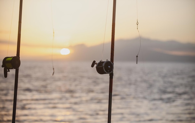 Canna da pesca e mulinello sul mare e sul cielo al tramonto