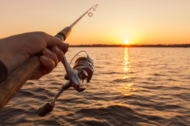 Canna da pesca in mano sul tramonto