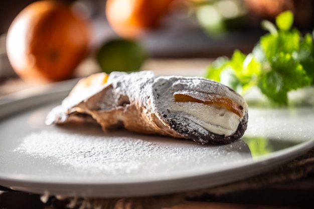 Cannoli siciliani dolce da dessert condito con zucchero servito su un piatto.