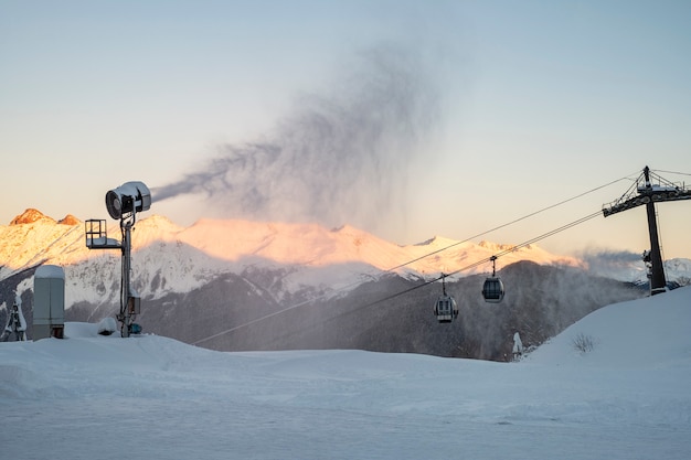 Cannone da neve di sera montagne e funivia. Preparazione per la stagione sciistica