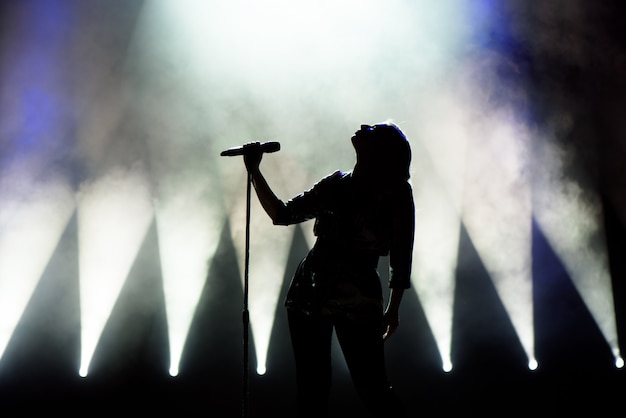 Cantante che canta al microfono. Cantante in silhouette