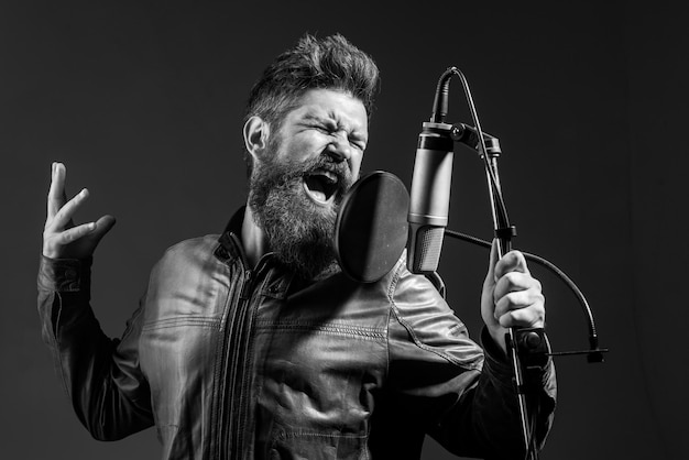 Cantante uomo in studio di registrazione espressivo uomo barbuto con microfono espressivo cantante con micr...