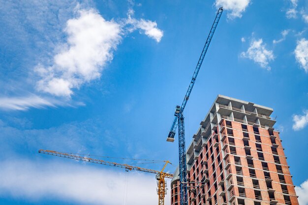 Cantiere con gru contro un cielo blu con nuvole bianche