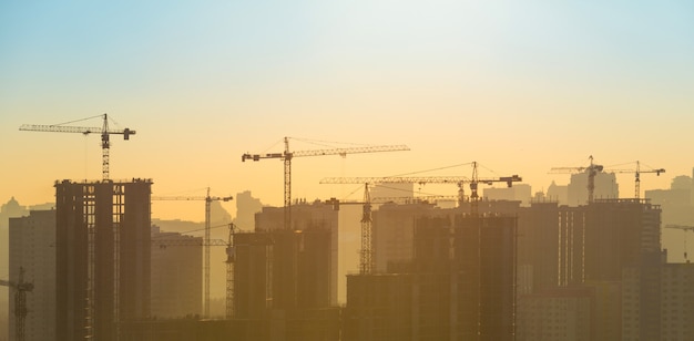 Cantiere con gru industriali in città al tramonto