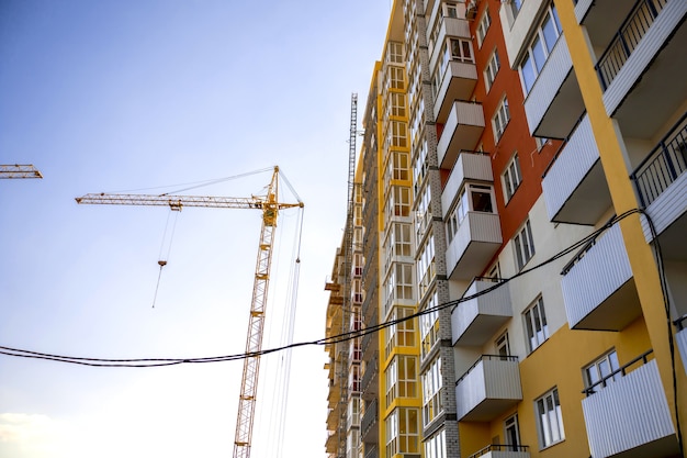 Cantiere e gru a torre di costruzione gialla. Macchine edili e tecnologia moderna, foto di attività di costruzione