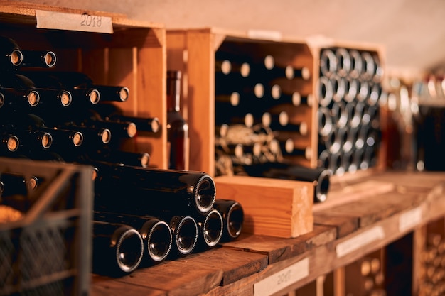 Cantina per vini con bottiglie di bevande alcoliche conservate in una rastrelliera di legno con etichette dell'anno vintage