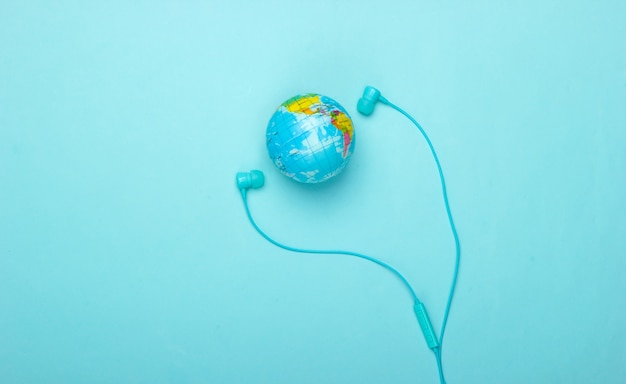 Canzone del mondo. Grafico musicale globale. La musica della terra. Auricolari stereo e un globo su una parete blu Vista dall'alto