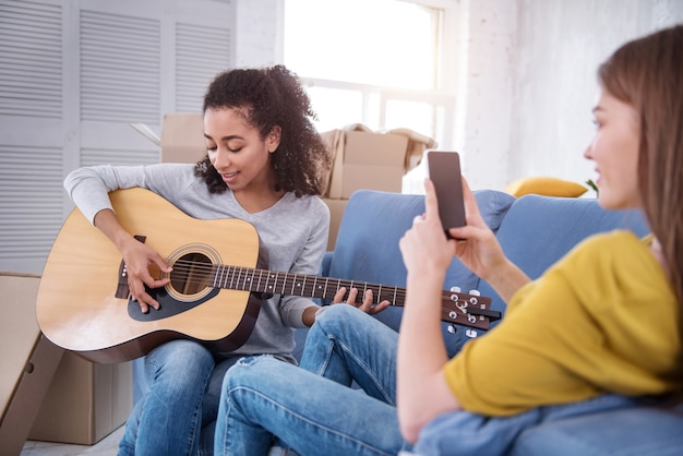 Canzone per te. Allegra ragazza dai capelli ricci suona la chitarra e dedica una canzone alla sua coinquilina mentre la filma al telefono