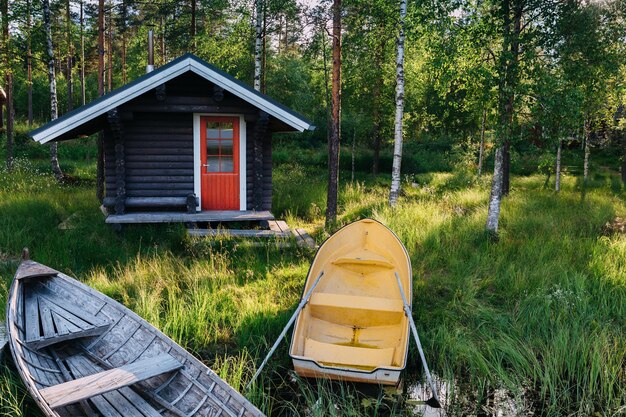 Capanna in legno tradizionale Sauna finlandese sul lago e molo con barche da pesca Paesaggio estivo