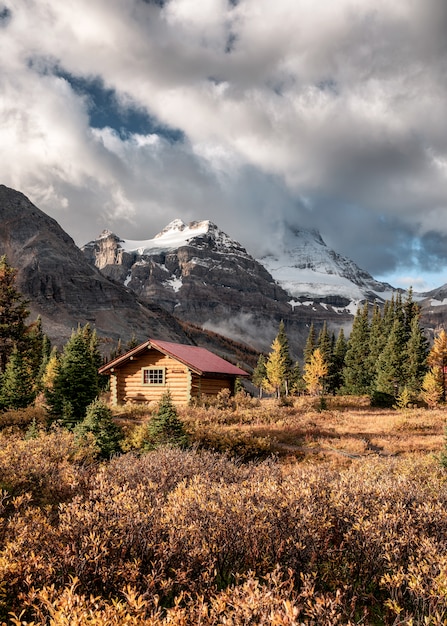 Capanne di legno con le montagne rocciose nella foresta di autunno al parco provinciale di Assiniboine