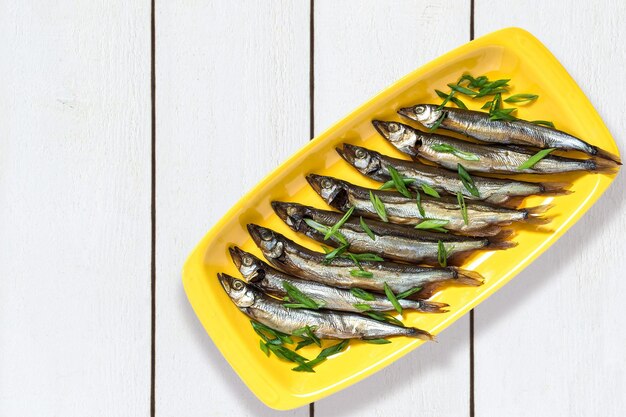 Capelin affumicato con cipolle verdi su piatto giallo