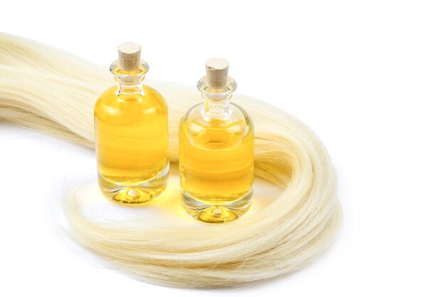 Capelli biondi e bottiglie di olio isolate su fondo bianco.