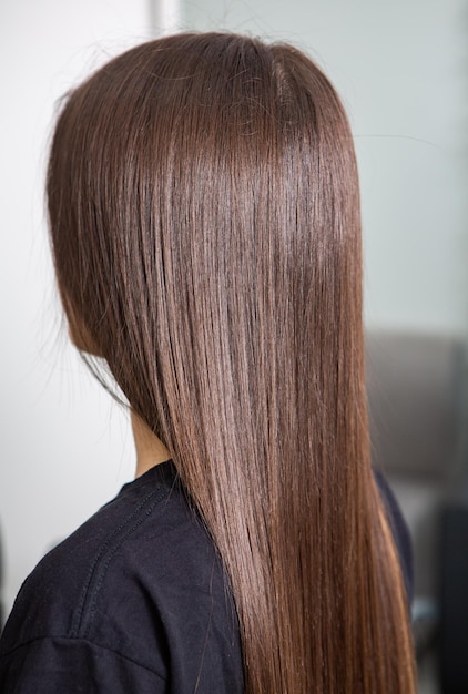Capelli castani lisci e sani che hanno subito la procedura di stiratura dei capelli