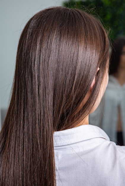 Capelli castani lisci e sani che hanno subito la procedura di stiratura dei capelli