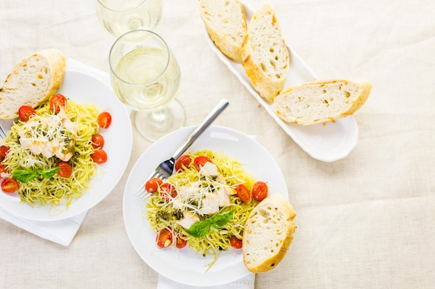 Capelli d'angelo fatti in casa con salsa al pesto, pomodorini arrostiti e pollo alla griglia.