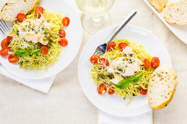 Capelli d'angelo fatti in casa con salsa al pesto, pomodorini arrostiti e pollo alla griglia.