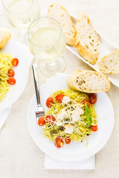 Capelli d'angelo fatti in casa con salsa al pesto, pomodorini arrostiti e pollo alla griglia.