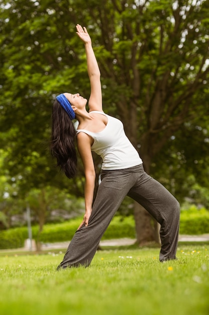 Capelli marroni allegri che fanno yoga su erba