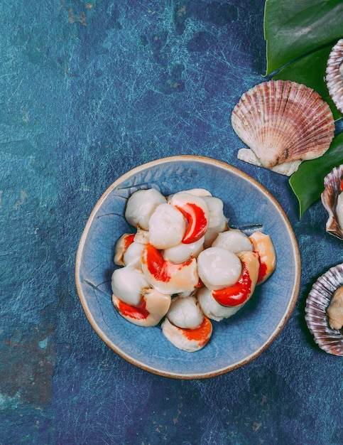 Capesante di frutti di mare freschi crudi su sfondo blu