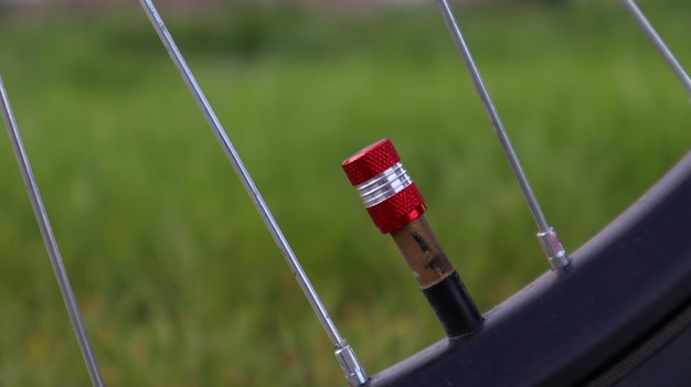 Capezzolo rosso della bicicletta. Dettaglio di un cerchione di bicicletta usato con stelo e coperchio della valvola. Pneumatico per mountain bike. Valvola ruota di bicicletta.