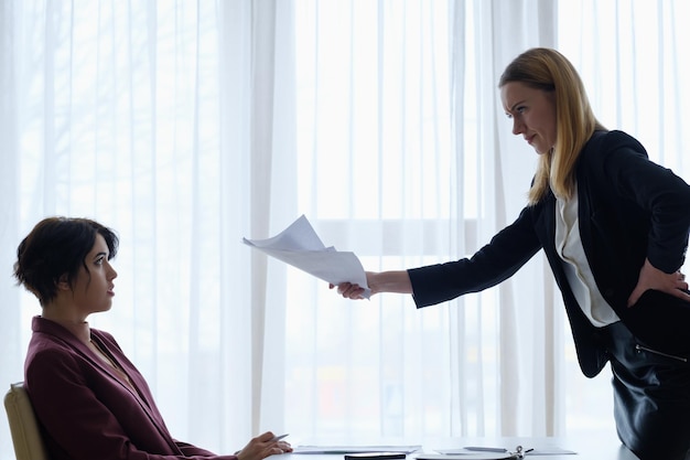 Capo arrabbiato che rimprovera la sua donna d'affari dipendente che riceve un rimprovero dal rapporto professionale superiore e subordinato del capo manager