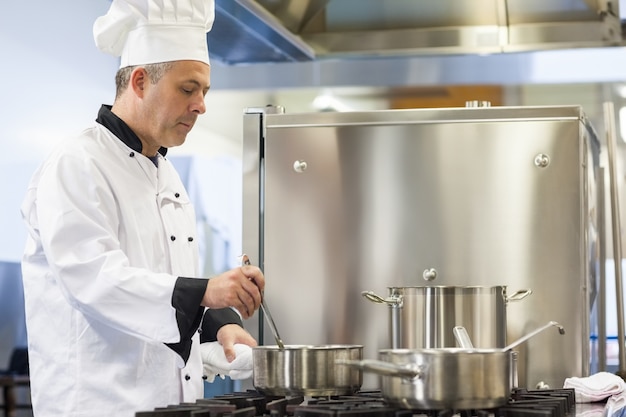 Capo chef focalizzato mescolando in pentola