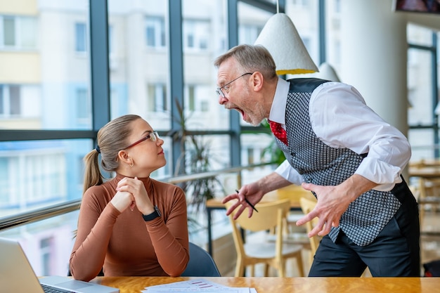 Capo dispiaciuto con gli occhiali che urla al manager della donna in ufficio.