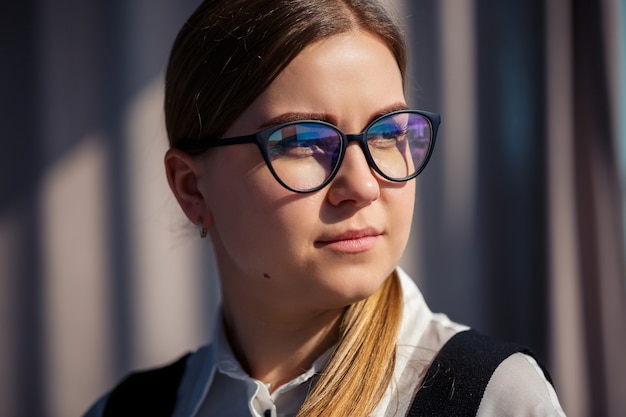 Capo donna d'affari fiducioso in piedi in un ufficio moderno con gli occhiali, leader femminile, imprenditore che pensa al successo futuro, pianificando nuove opportunità