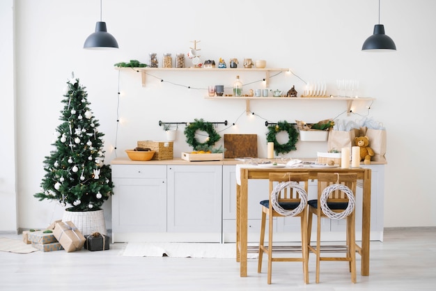 Capodanno e Natale. Festosa cucina scandinava nelle decorazioni natalizie. Candele, rami di abete, supporti in legno, tavolo.