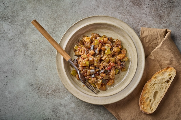 Caponata tradizionale siciliana fatta in casa con melanzane, zucchine, pomodori, olive e ciabatta. Vista dall'alto, copia spazio