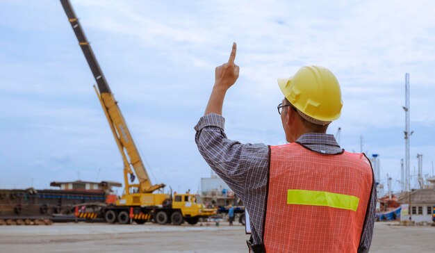 Caposquadra che mostra il segno della mano numero uno mentre controlla il trasferimento delle merci nell'area del porto di spedizione