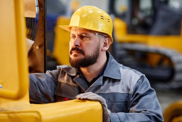 Caposquadra o riparatore serio in tuta e casco di sicurezza che controllano il motore