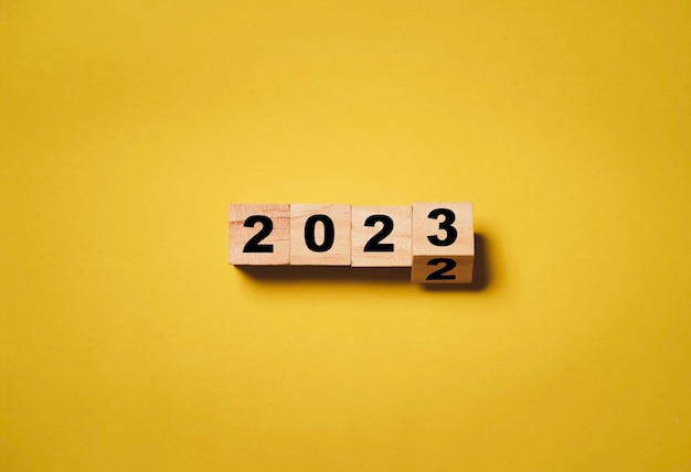 Capovolgimento dal 2022 al 2023 sul cubo di blocchi di legno per la preparazione del nuovo anno cambia e avvia un nuovo concetto di strategia aziendale per l'obiettivo