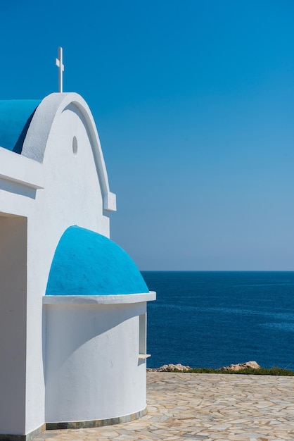 Cappella tradizionale greca bianca con tetto blu sul mare Agioi Anargyroi cappella Cipro