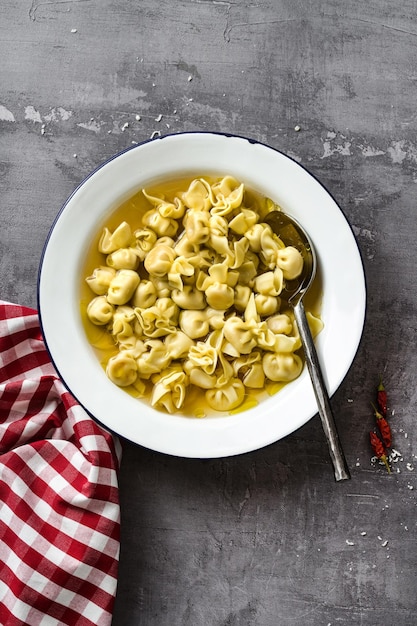 Cappelletti in brodo Piatto italiano per le vacanze in famiglia sul tavolo con parmigiano