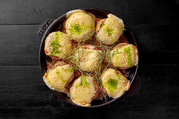 Cappelli di funghi al forno ripieni di suluguni cosparsi di sesamo e cipolle verdi fritte in padella di ferro