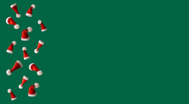 Cappelli di Natale rossi su sfondo verde, concetto creativo di Natale con spazio libero per il testo