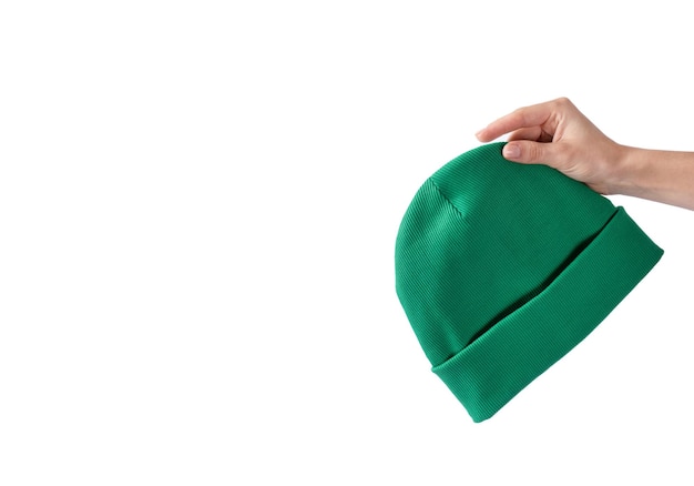 Cappello beanie verde in mano di una ragazza su sfondo bianco Copricapo autunnale unisex Copia spazio