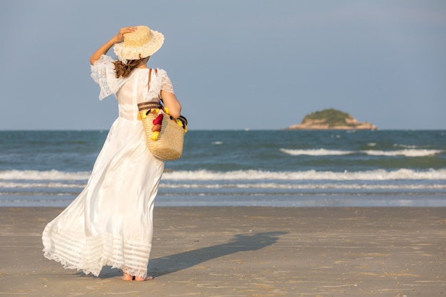 Cappello d&#39;uso della donna e borsa della tenuta sulla spiaggia