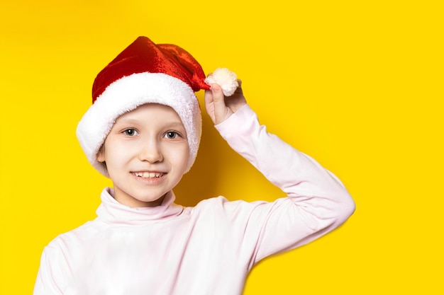 Cappello da Babbo Natale. Natale. Bambina felice su uno sfondo giallo vestito da Babbo Natale. concetto di nuovo anno