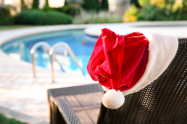 Cappello da Babbo Natale sul lettino vicino alla piscina del resort. concetto di natale
