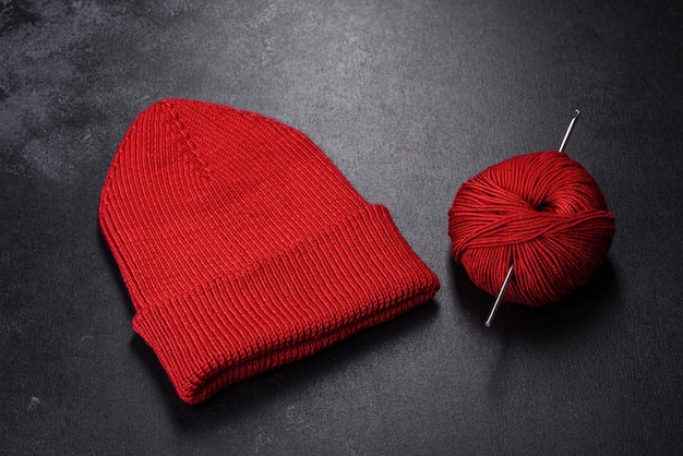 Cappello da donna rosso caldo lavorato a maglia su sfondo di cemento Hobby e tempo libero