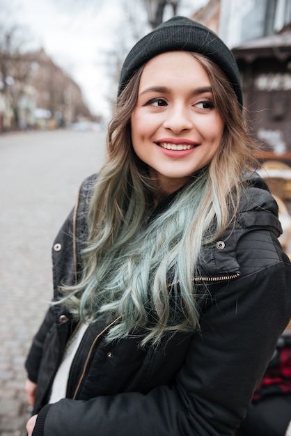 Cappello da portare della giovane donna felice che cammina sulla via