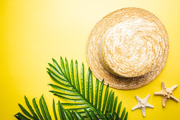 Cappello da spiaggia di paglia e occhiali da sole vista dall'alto su sfondo giallo piatto estivo