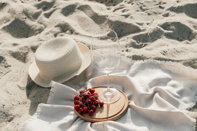 Cappello da spiaggia in paglia con tesa per protezione solare con un piatto di frutta e vino