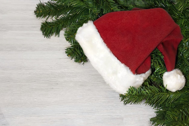 Cappello di Babbo Natale e albero di Natale sulla tavola di legno bianca. Composizione per le vacanze di Capodanno 2021.