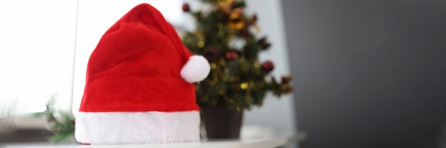 Cappello di Babbo Natale in piedi vicino al primo piano dell'albero di Natale